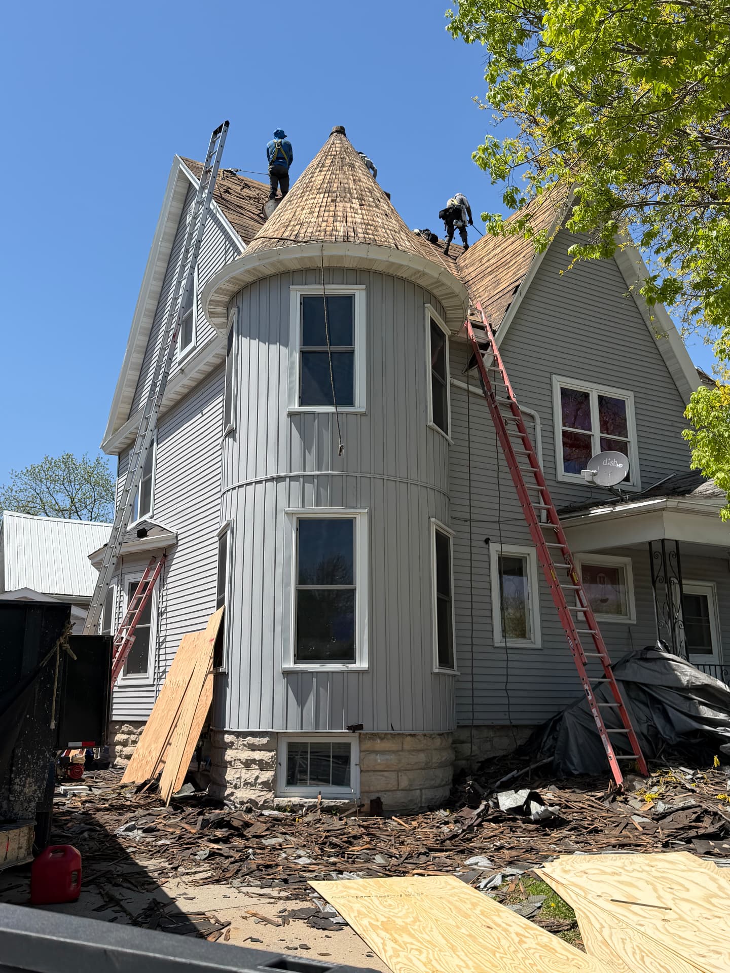 Crew tearing off an old roof on a turreted home